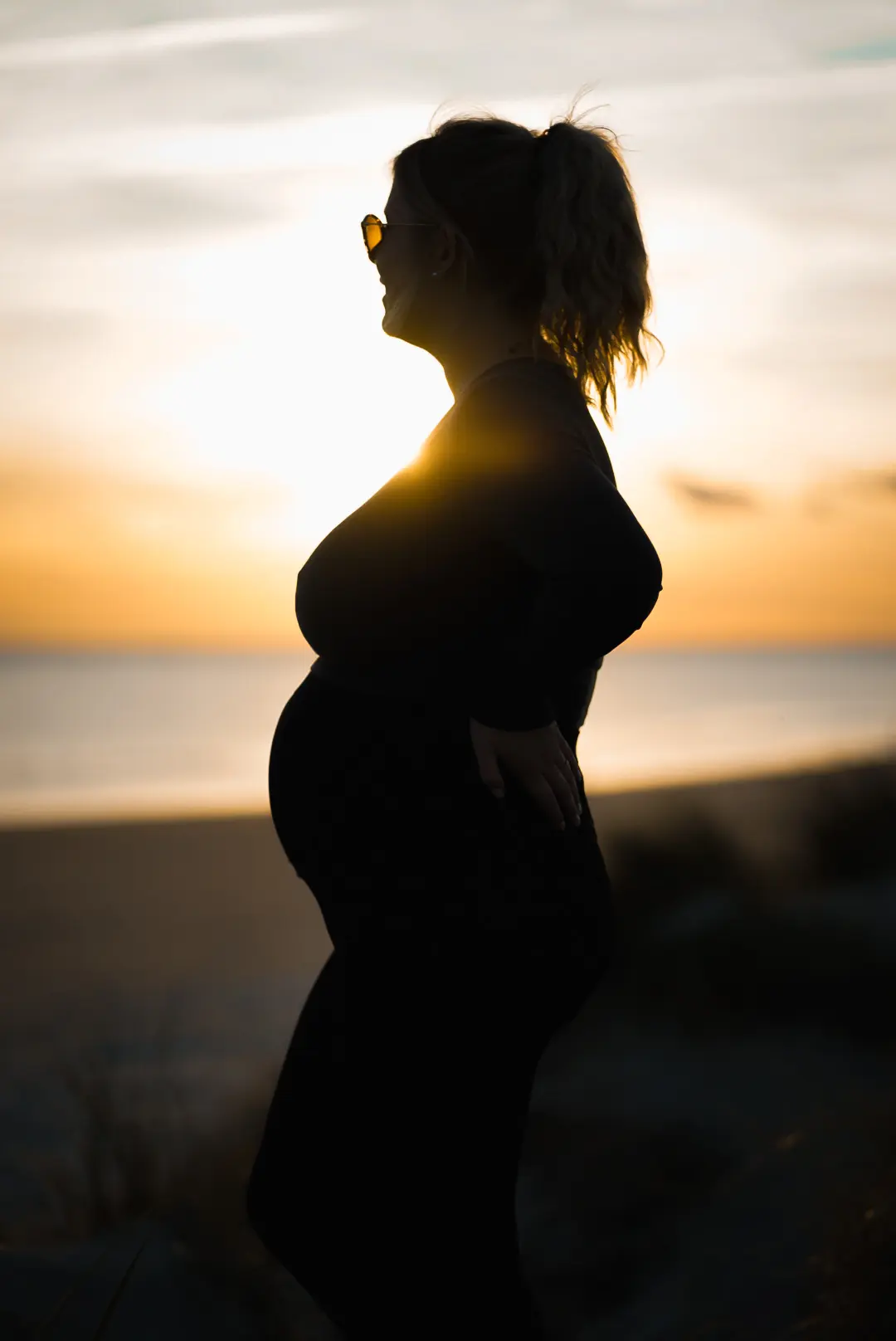 Babybauch-Portrait als Silhouette im goldenen Abendlicht