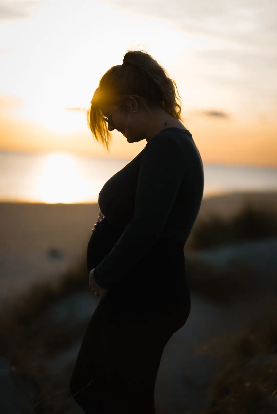 Werdende Mutter im warmen Licht des Sonnenuntergangs