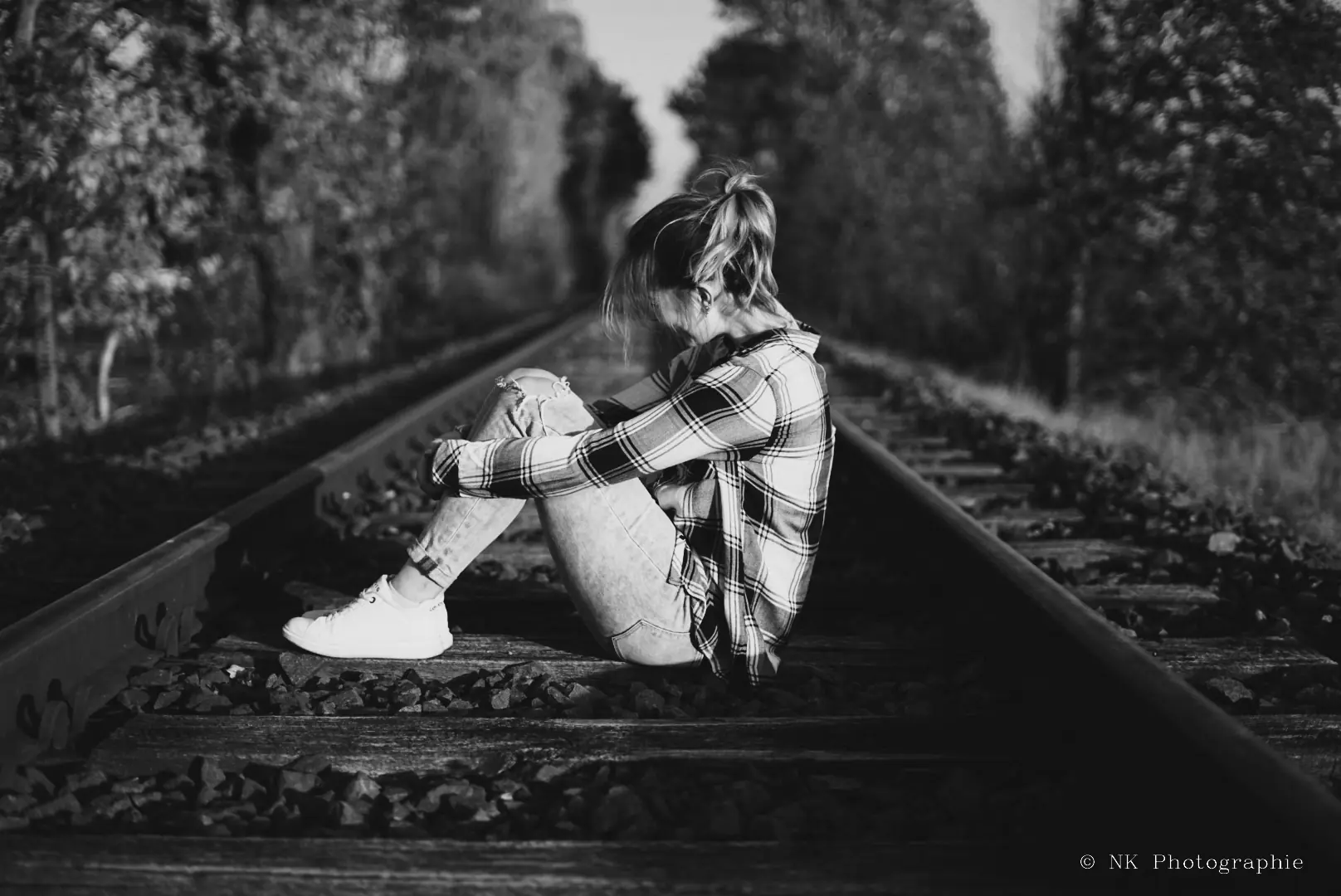 Schwarz-Weiß-Portrait einer Frau auf Bahngleisen