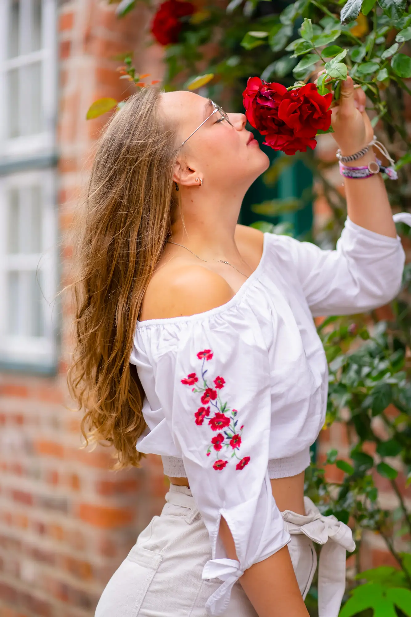 Natürliches Portrait mit roten Rosen vor einer Backsteinfassade